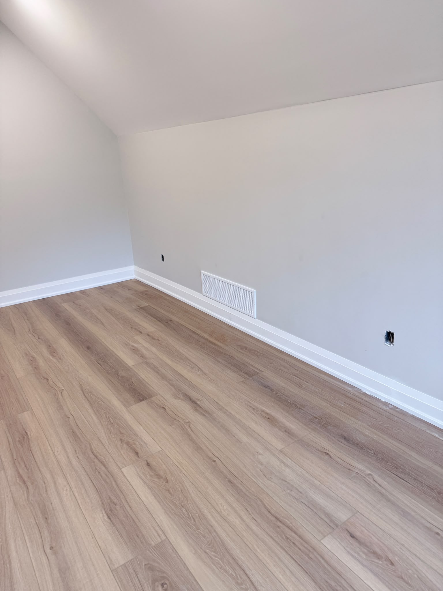 White baseboard running around a room with a sloped ceiling
